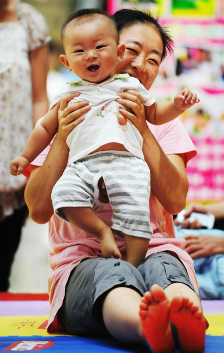 A mother takes part in a game with her baby during a baby talent show in Harbin, capital of northeast China's Heilongjiang Province, July 26, 2009. [Wang Jianwei/Xinhua]