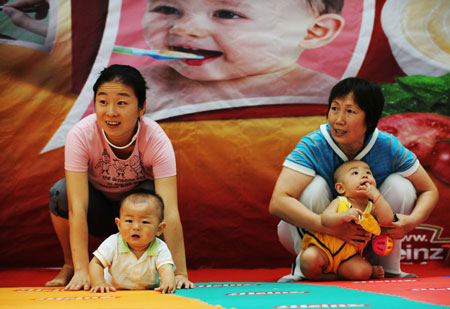 Mothers take part in a game with their babies during a baby talent show in Harbin, capital of northeast China's Heilongjiang Province, July 26, 2009. [Wang Jianwei/Xinhua]