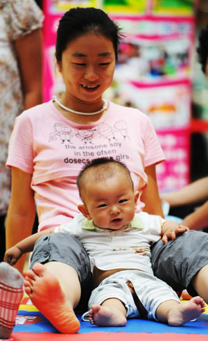 A mother takes part in a game with her baby during a baby talent show in Harbin, capital of northeast China's Heilongjiang Province, July 26, 2009. [Wang Jianwei/Xinhua] 