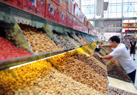 A vendor arranges his shop in the International Grand Bazaar in Urumqi, capital of northwest China's Xinjiang Uygur Autonomous Region, July 26, 2009. The bazaar revived after reopened on July 22 for the first time since the deadly riot in the city on July 5. It is a 100,000-square-meter commercial complex with a strong Islamic architectural influence that includes a banquet hall, a food court, a sightseeing tower, an open-air stage and a mosque.[Xinhua]