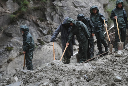 Soldiers search for the missing people in the rain at the site of the landslide in Kangding, southwest China's Sichuan Province, July 26, 2009. [Jiang Hongjing/Xinhua]