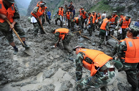 Soldiers and residents search for victims and clear the road destroyed by a massive landslide, triggered by heavy rain in Kangding county of the Garze Tibetan autonomous prefecture in southwest China's Sichuan province, July 25, 2009. At least four road construction workers were killed and at least 50 others injured in the incident. [Xinhua] 