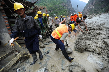 Soldiers and residents search for victims and clear the road destroyed by a massive landslide, triggered by heavy rain in Kangding county of the Garze Tibetan autonomous prefecture in southwest China's Sichuan province, July 25, 2009. At least four road construction workers were killed and at least 50 others injured in the incident.[Xinhua]