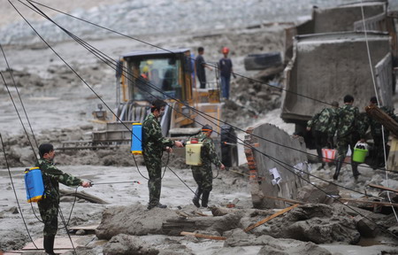 Soldiers disinfect the road after a massive landslide, triggered by heavy rain in Kangding county of the Garze Tibetan autonomous prefecture in southwest China's Sichuan province, July 25, 2009. At least four road construction workers were killed and at least 50 others injured in the incident.[Xinhua]