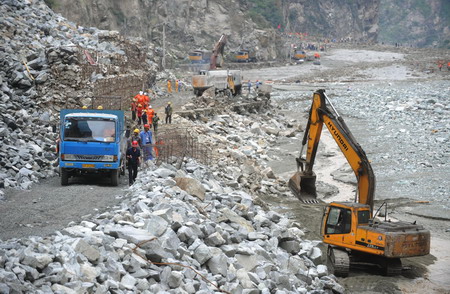 Rescuers clear the road destroyed by a massive landslide, triggered by heavy rain in Kangding county of the Garze Tibetan autonomous prefecture in southwest China's Sichuan province, July 25, 2009. At least four road construction workers were killed and at least 50 others injured in the incident. [Xinhua]