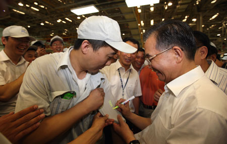 Chinese Premier Wen Jiabao (R) signs his name for a worker with FAW Car Co., Ltd. in northeast China's Jilin Province, July 26, 2009. Wen made an inspection tour in Jilin Province from July 25 to 27. [Yao Dawei/Xinhua]