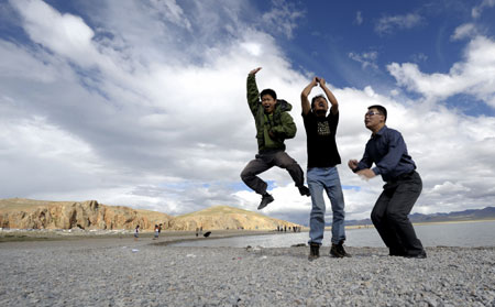 Tourists pose for a photo near Nam Co Lake, the highest saltwater lake of the world at 4,718 meters above the sea level, located at the boundary of Damxung and Baingoin counties, southwest China's Tibet Autonomous Region, July 26, 2009. Generally, tourists like visiting Nam Co Lake in summer, the most comfortable season in this region. [Purbu Zhaxi/Xinhua]