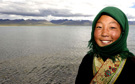 A Tibetan girl poses for a photo beside Nam Co Lake, the highest saltwater lake of the world at 4,718 meters above the sea level, located at the boundary of Damxung and Baingoin counties, southwest China's Tibet Autonomous Region. Generally, tourists like visiting Nam Co Lake in summer, the most comfortable season in this region. [Purbu Zhaxi/Xinhua]