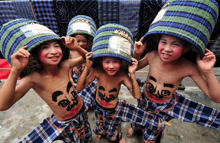 Children perform Wendangmu, a traditional local folk dance of some hundred years history, during a folk culture art festival held in Weng'ang Township in Libo County, southwest China's Guizhou Province, July 27, 2009. With baskets covering the heads and shoulders and humorous faces painting on the bellies the dancers acted like elfins, whose performance attracted so many tourists. [Qin Gang/Xinhua]