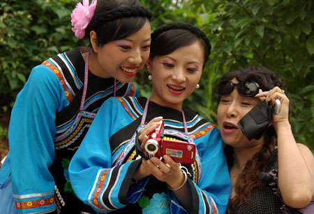 A woman of the Buyi ethnic group shoots folk performances with a video camera at the opening of the Original Folk Culture Festival held in Qingzhen City of southwest China's Guizhou Province, July 26, 2009. Series of activities like folk culture tours, ethnic-styled competitions, folk custom photo shows, drug bathing, etc. will be held during the festival. (Xinhua/Jin Yulong)