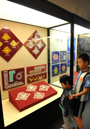 Two boys appreciate Chinese paper-cut crafts in the Yunnan Ethnical Museum in Kunming, southwest China's Yunnan Province, July 27, 2009. The Yunnan Ethnical Museum has 16 exhibition halls with a total area of 6,000 square metres. (Xinhua/Chen Haining) 