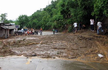 People walk on mudslide in Miyi County, Panzhihua City, southwest China's Sichuan Province Monday July 27, 2009. [Xinhua]
