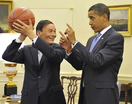 Chinese Vice Premier Wang Qishan (L), special representative of Chinese President Hu Jintao, holds a basketball presented by the U.S. President Barack Obama as a gift in the Oval Office of the White House in Washington, on July 28, 2009. [Xinhua]