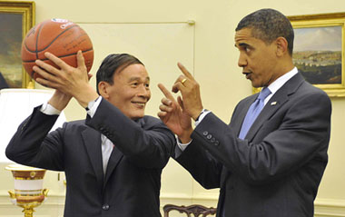Chinese Vice Premier Wang Qishan (L), special representative of Chinese President Hu Jintao, holds a basketball presented by the U.S. President Barack Obama as a gift in the Oval Office of the White House in Washington, on July 28, 2009. [Xinhua]