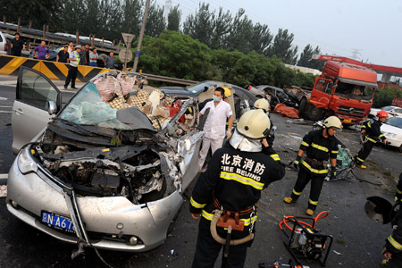 Rescuers work at the scene where a truck overturned and collided with three cars in the opposite direction on the east Ring Road No. 5 in Beijing, capital of China, July 28, 2009. At least seven people died and one was injured after a truck overturned on a busy Beijing ring road Tuesday, police said. [Wei Tong/Xinhua] 