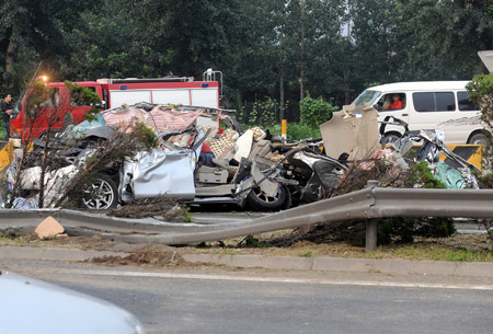 Photo taken on July 28, 2009 shows the scene where a truck overturned and collided with three cars in the opposite direction on the east Ring Road No. 5 in Beijing, capital of China. Seven people died and another was injured in the traffic accident, police said. [Wei Tong/Xinhua]