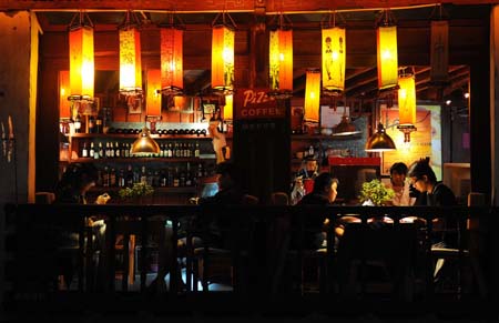 Tourists enjoy their leisure time at a pub in Lijiang, a tourist resort in southwest China's Yunnan Province, July 27, 2009. The 800-year-old city, located on the northwest tip of Yunnan, was listed by the UNESCO in 1997 as a world cultural heritage site. (Xinhua/Lin Yiguang) 