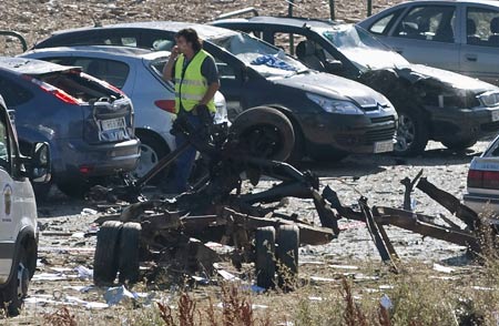 A policeman walks past damaged vehicles near a Civil Guard barracks after a car bomb exploded in the northern Spanish city of Burgos, early July 29, 2009.[Xinhua/Reuters]