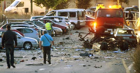 Investigators walk through debris and damaged vehicles outside a civil guard barracks after a car bomb exploded in the northern Spanish city of Burgos, early July 29, 2009.[Xinhua/Reuters]