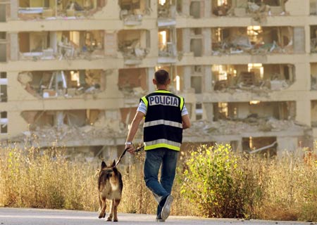 A policeman searches for evidence with a dog in front of a civil guard barracks after a car bomb exploded in the northern Spanish city of Burgos, early July 29, 2009.[Xinhua/Reuters]