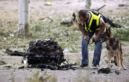 A policeman looks at debris from a vehicle near a Civil Guard barracks after a car bomb exploded in the northern Spanish city of Burgos, early July 29, 2009.[Xinhua/Reuters]