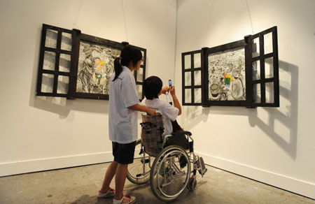 Survivors of the Sichuan earthquake on May 12, 2008 view the canvas works at the fourth Chengdu Biennial Exhibition in Chengdu, capital of southwest China's Sichuan Province, July 29, 2009.[Jiang Hongjing/Xinhua] 