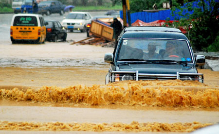 Vehicles drive in deep water on a flooded street as a heavy rainstorm hits Jiujiang city in east China's Jiangxi Province, July 29, 2009. Local emergency department employees of the city are on standby to answer emergent calls as some local streets were flooded. [Xinhua]