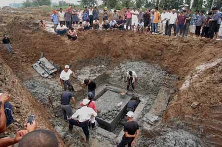People work at an archaeological site in Xihu Township in the Weiyang District of Yangzhou City, east China's Jiangsu Province, July 29, 2009. An ancient tomb, which is estimated to be a tomb of the Han Dynasty (206 BC-220 AD), has been excavated and burial artifacts like copper mirror, pottery, lacquer article have been found. The coffin has not been opened yet. [Wang Naisi/Xinhua] 
