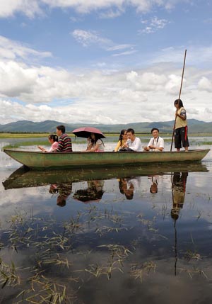 Tourists tour by boat the Lashihai wetland park in Lijiang, southwest China's Yunnan Province, on July 29, 2009. [Lin Yiguang/Xinhua]