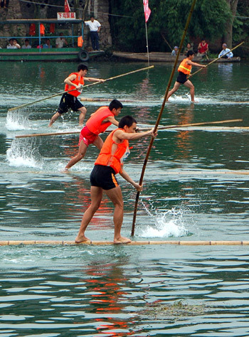 Participants paddle forward during a bamboo drift racing in Majiang county, southwest China's Guizhou province, July 29, 2009. [Xinhua]