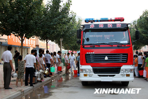 People line up for clean drinking water sent by local fire trucks on July 28, 2009. Altogether 2,622 people have sought medication for gastrointestinal illness after the tap water supply was contaminated by rainfall on July 25 in Chifeng City of north China's Inner Mongolia Autonomous Region.
