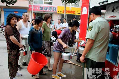 People line up for clean drinking water sent by local fire trucks on July 28, 2009. Altogether 2,622 people have sought medication for gastrointestinal illness after the tap water supply was contaminated by rainfall on July 25 in Chifeng City of north China's Inner Mongolia Autonomous Region.