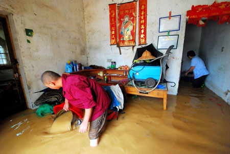 Local residents clear water out of their flooded house after a heavy rainstorm hit Jiujiang city in east China's Jiangxi Province, July 29, 2009. Local emergency department employees of the city are on standby to answer emergent calls as some local streets were flooded. 