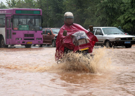 A man drives a motorcycle on a flooded street as a heavy rainstorm hits Jiujiang city in east China's Jiangxi Province, July 29, 2009. Local emergency department employees of the city are on standby to answer emergent calls as some local streets were flooded. 