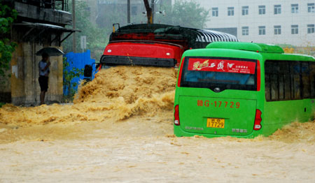 A heavy truck and a bus drive in deep water on a flooded street as a heavy rainstorm hits Jiujiang city in east China's Jiangxi Province, July 29, 2009. Local emergency department employees of the city are on standby to answer emergent calls as some local streets were flooded. 
