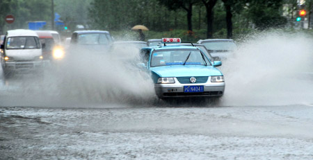 A car runs past a section of a flooded street in Shanghai, China, July 30, 2009. [Xinhua]
