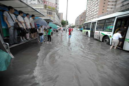 People get on the bus at a flooded section of the Xietu Road in Shanghai, China, July 30, 2009.[Xinhua]