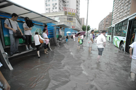 People get on the bus at a flooded section of the Xietu Road in Shanghai, China, July 30, 2009.[Xinhua]