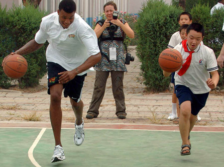 NBA player Brandom Rush (L) plays games with a student of a primary school of rural migrant workers' children during the 2009 Basketball Without Borders Asia tour in Beijing, capital of China, July 30, 2009. NBA players donated computers to this school and helped build a basketball pitch before their visit. [Gong Lei/Xinhua]