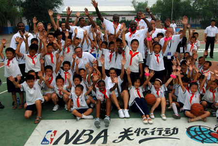 NBA players and coaches pose with students of a primary school of rural migrant workers' children during the 2009 Basketball Without Borders Asia tour in Beijing, capital of China, July 30, 2009. NBA players donated computers to this school and helped build a basketball pitch before their visit. [Gong Lei/Xinhua] 