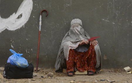 An internally displaced woman, who months earlier fled a military offensive against the Taliban, takes a rest at a bus terminal in Karachi with waiting to return to her village in the Swat Valley region on July 30, 2009. About 1,400 internally displaced persons (IDP), who were seeking shelter with their families in the southern seaport city of Karachi, departed on a 20-hour journey back to their villages, Reuters witnesses said. [Xinhua/Reuters]