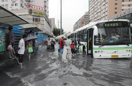 People get on the bus at a flooded section of the Xietu Road in Shanghai, China, July 30, 2009. The heaviest rains in 70 years hit China's largest city, Shanghai, Thursday, flooding 3,000 households and more than 70 roads. [Xinhua]