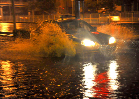 A taxi runs on a flooded street in Beijing, capital of China, July 31, 2009. A heavy rain hit Beijing on Thursday evening and caused traffic jam. The heaviest rainstorm of the year hit Beijing from Thursday night through Friday early morning. [Luo Xiaoguang/Xinhua] 