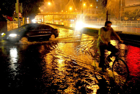 A man rides a bike on a flooded street in Beijing, capital of China, July 31, 2009. A heavy rain hit Beijing on Thursday evening and caused traffic jam. [Luo Xiaoguang/Xinhua]