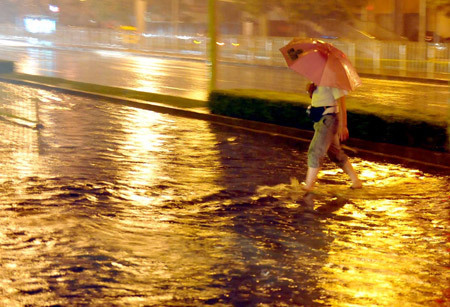 A man walks on a flooded street in Beijing, capital of China, July 31, 2009. A heavy rain hit Beijing on Thursday evening and caused traffic jam. [Luo Xiaoguang/Xinhua]