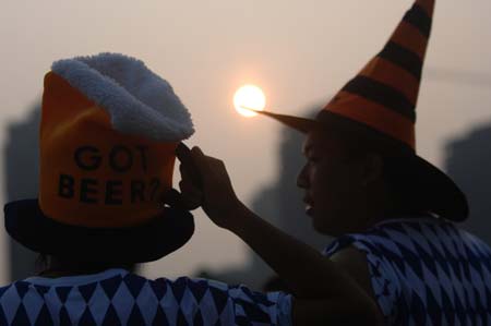 Two youths sell hats during the 11th China International Beer Festival in Dalian, a coastal city in northeast China's Liaoning Province, July 30, 2009. The festival opened here on Thursday. More than 30 breweries from China, Germany, the United States and the Republic of Korea attended the festival with over 400 beer brands.[Yao Jianfeng/Xinhua]