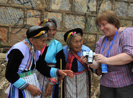 A foreign tourist (R1) displays photos she took for the old women of the Yi ethnic group at Keyi Village of Mile County, southwest China's Yunnan Province, July 29, 2009. (Xinhua/Li Mingfang)