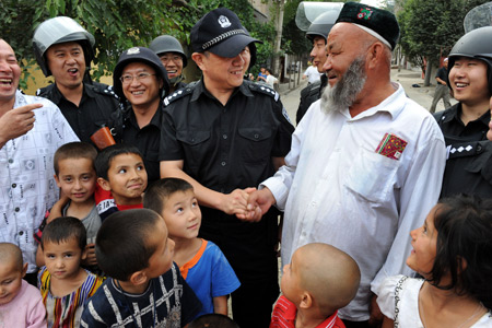 Xu Tao (C), a member of the special police force, shakes hands with an elder Uygur man, on Pingding Hill in Urumqi, capital of northwest China's Xinjiang Uygur Autonomous Region, July 14, 2009.