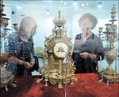 Visitors admire a 19th-century copper table clock and candle stick. [Shanghai Daily]