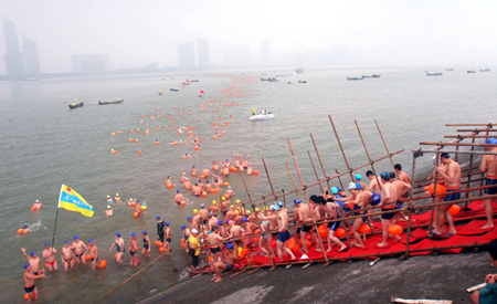 Swimmers take water and prepare to cross over the Qiantang River in Hangzhou, capital of east China's Zhejiang Province, August 2, 2009.(Xinhua/Liang Yongfeng)